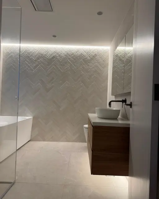 Timber vanity and vessel basin under concealed lighting