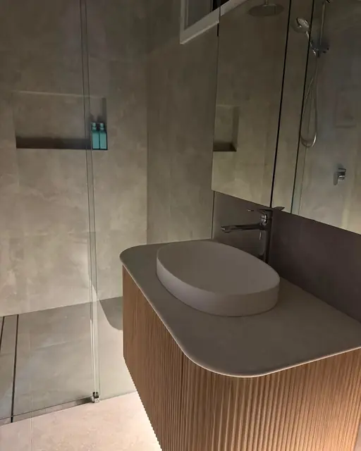 Fluted timber vanity with a stone top and oval basin