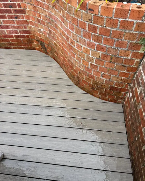 Composite decking scribed around a curved brick garden wall
