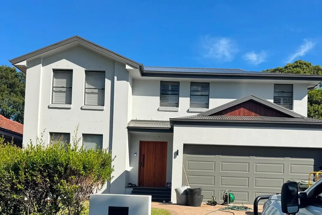 The finished house — white render, new roof and a solid timber front door