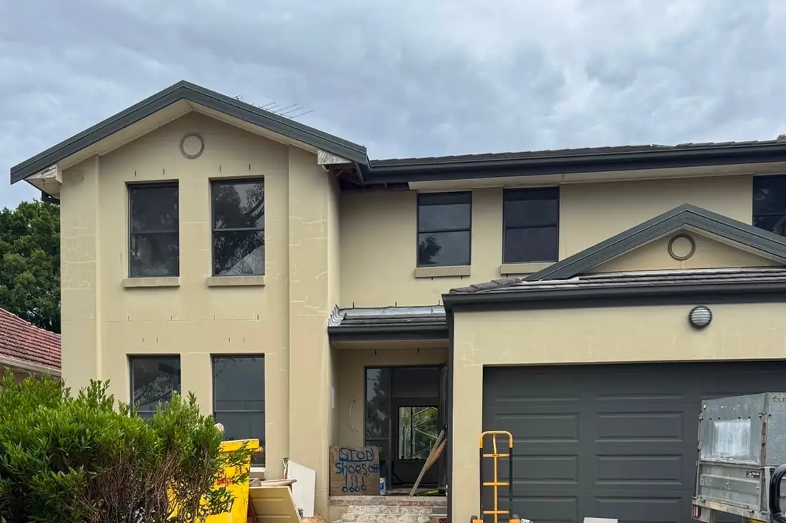 The house before renovation — cracked cream render and the original roof
