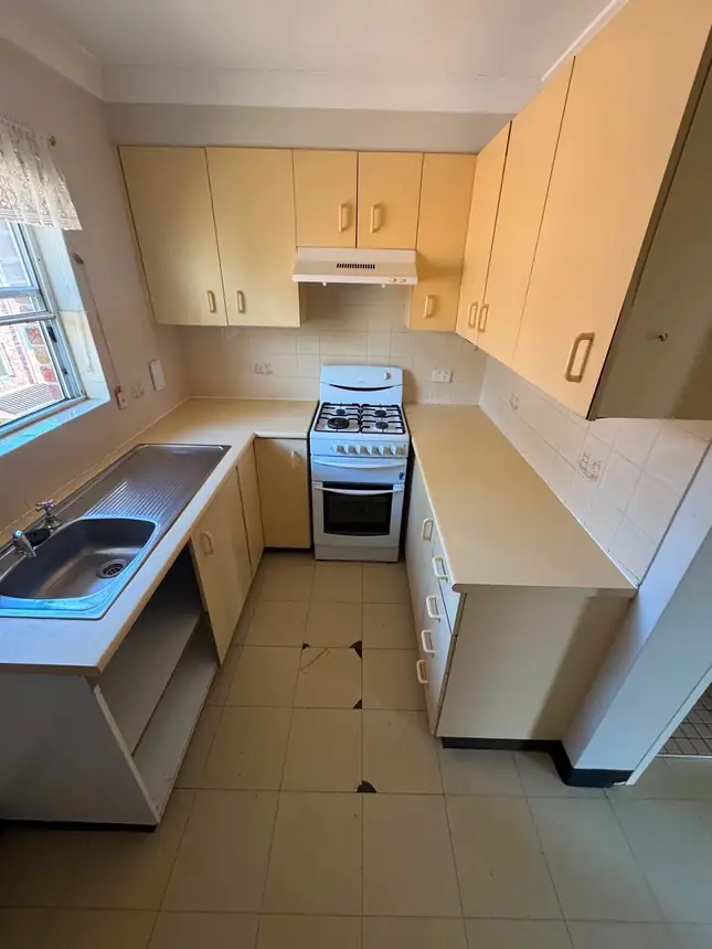 The original kitchen before renovation — dated cream laminate and a freestanding cooker